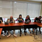 photo of five face to face youth leaders seated behind tables with microphones on the tables in st paul minnesota to record their visions for their futures with tek burch at safezone